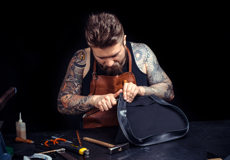 Artisan at work on his new leather product in his workplaceの写真素材