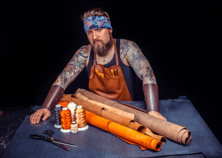 Artisan of leather works with leather at workplace