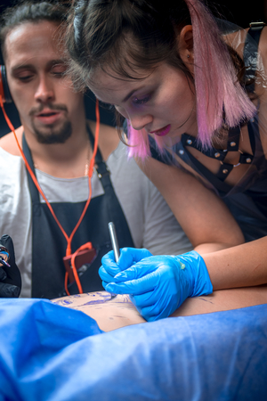 Skin master demonstrates the process of getting tattoo in tattoo studioの写真素材