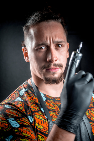 Master of the art of tattooing with a tattoo gun in tattoo studioの写真素材