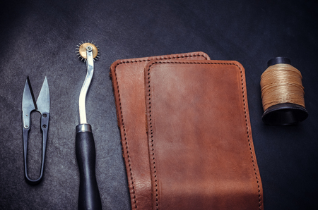 pieces of yellow leather, tools and spool of yellow thread on a black background