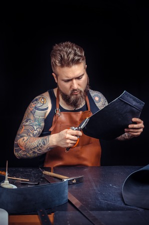 Leather Tanner working with leather using crafting tools in his shopの写真素材