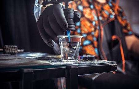 Hand of master of the art of tattooing with a tattoo gun.の写真素材