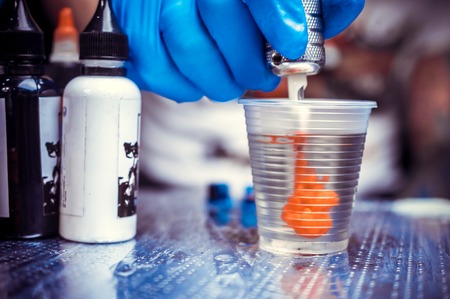 Hand of a tattooer, holding a tattoo gun.の写真素材