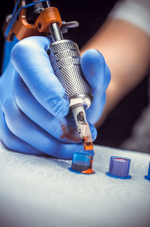 Tattooers hand and a tattoo machine.の写真素材