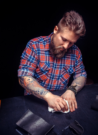 Artisan of leather producing a leatherwork at his workshelfの写真素材