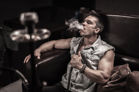 Sexy man is blowing smoke at the bar.