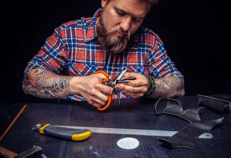 Professional Leather Worker cutting leather outlines for his new production at his workshelfの写真素材