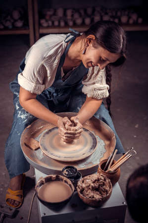 Charming ceramist master at his wheel creating a new masterpiece. Concept for woman in freelance, business, hobby.の写真素材