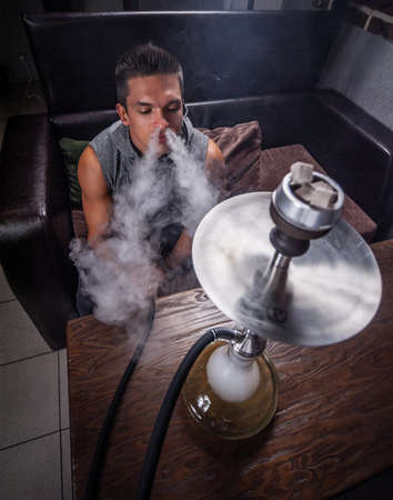 Handsome guy relaxes in a hookah in the shisha bar.の写真素材