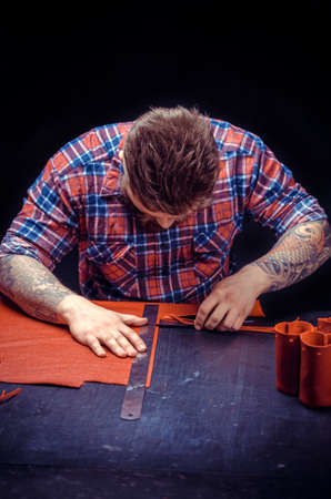 Leather Currier processing a leather workpiece at his studioの写真素材
