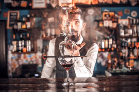 Expert bartending mixes a cocktail while standing near the bar counter in pubの写真素材