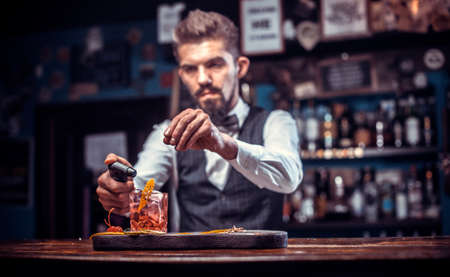 Focused barman creates a cocktail at barの写真素材