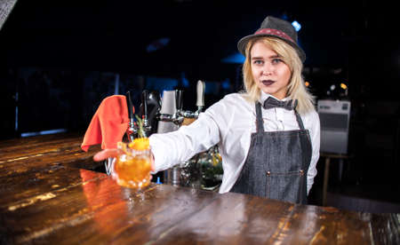 Girl bartender mixes a cocktail behind the barの写真素材