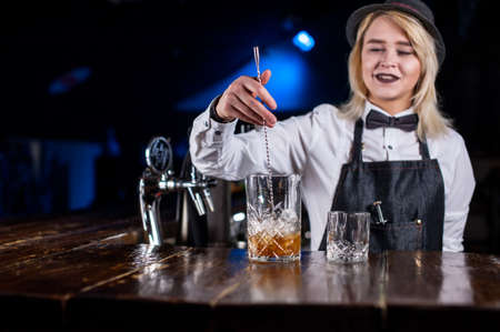 Young girl bartending demonstrates the process of making a cocktailの写真素材