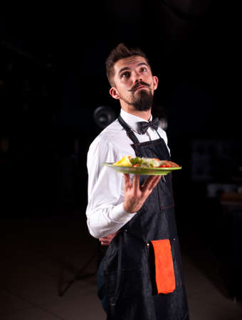 Civilized steward serves plate with prepared dish in the restaurant.の写真素材