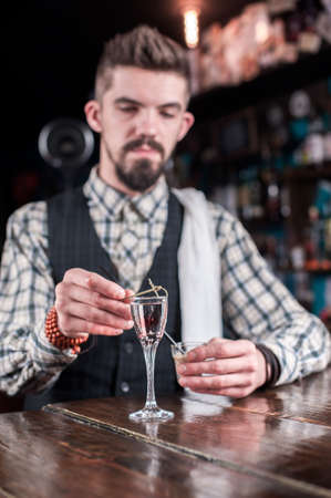 Expert barman mixes a cocktail while standing near the bar counter in barの写真素材