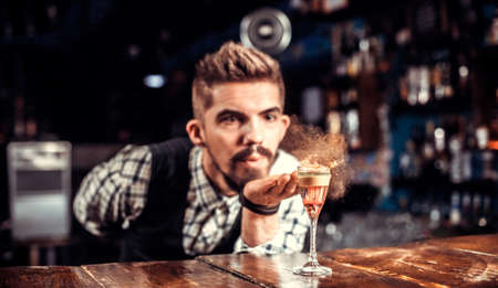 Charismatic bartender pouring fresh alcoholic drink into the glasses at the nightclubの写真素材