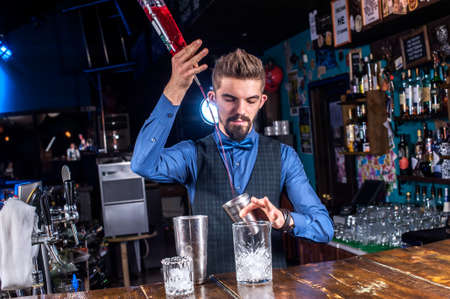 Charming barman demonstrates the process of making a cocktail at the nightclubの写真素材
