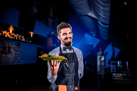 Young waiter holds dish at a festive event.