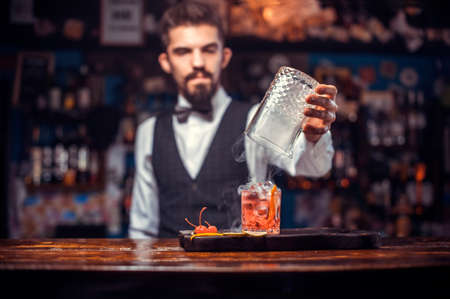 Portrait of mixologist pouring fresh alcoholic drink into the glassesの写真素材