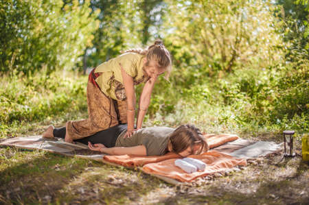 Two women give each other massages out in the forest.の写真素材