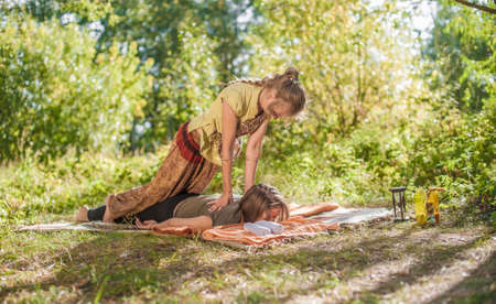 Experienced masseuse thuroughly massages a girl in the daylight.の写真素材