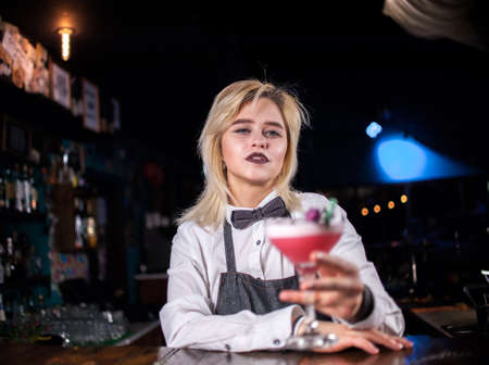 Young girl bartender demonstrates the process of making a cocktailの写真素材