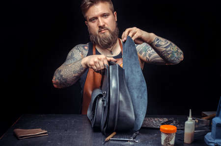 Worker of leather working with leather using crafting tools at a workshopの写真素材