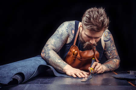 Man working with leather processes a workpiece from leather in the place of workの写真素材