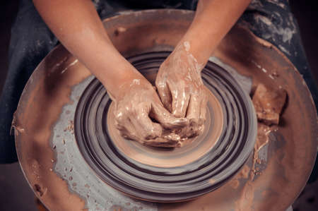 Hands of the master potter and vase of clay on the potters wheel close-up. Master crock. Twisted potters wheel.の写真素材