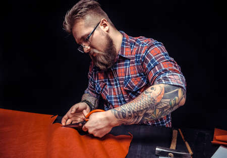 Tailor produces cutting brown leather for the manufacture of products.の写真素材