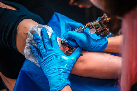 Master tattooist does tattoo on the skin of his client in tattoo parlourの写真素材