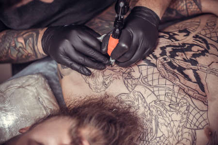 Tattoo artist demonstrates the process of getting tattoo in tattoo studioの写真素材