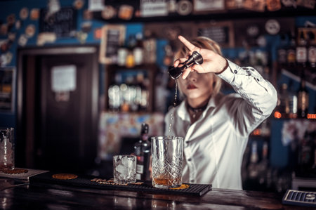 Expert girl bartending surprises with its skill bar visitors while standing near the bar counter in barの写真素材