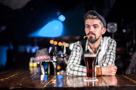 Young tapster decorates colorful concoction at the bar counterの写真素材