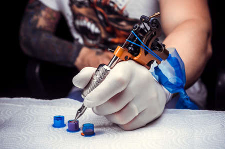 Hand of a tattoo artist and a tattoo gun.の写真素材