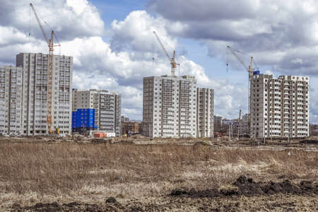 Modern houses under construction and construction cranesの写真素材