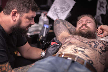 Tattoo specialist making a tattoo in studioの写真素材
