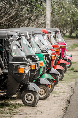A row of neatly parked tuk tuk auto rickshaws