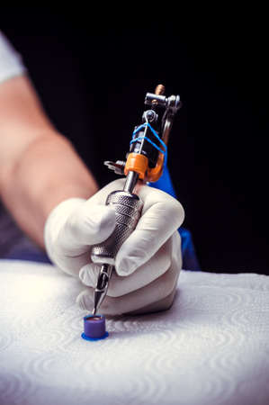 Tattooers hand and a tattoo machine.の写真素材