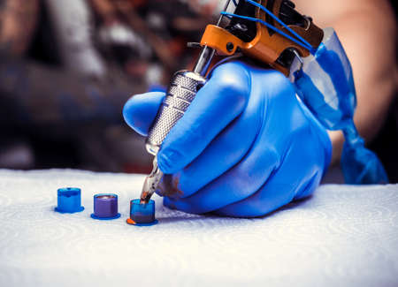 Hand of a professional tattooer with a tattoo gun.の写真素材
