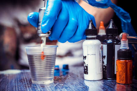 Hand of a tattoo specialist, holding a tattoo machine.の写真素材