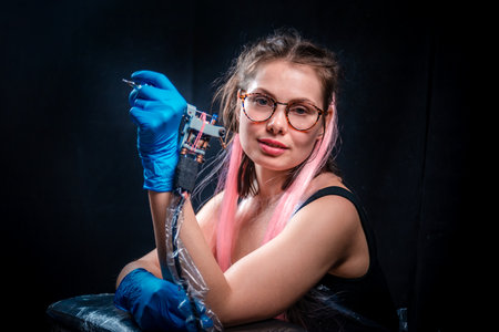 Tattooer and a tattoo gun in salonの写真素材