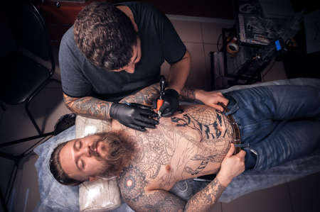 Master working tattooing in tattoo parlourの写真素材