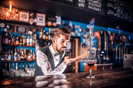 Bearded bartending places the finishing touches on a drinkの写真素材