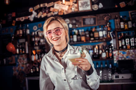 Charming woman mixologist is pouring a drinkの写真素材
