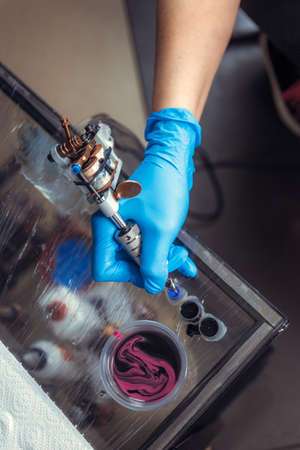 Hand of professional tattooer and a tattoo gun.の写真素材