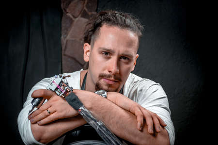Tattoo artist with a tattoo machine in a workshop studioの写真素材
