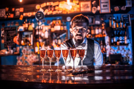 Confident bartender demonstrates his professional skills while standing near the bar counter in barの写真素材